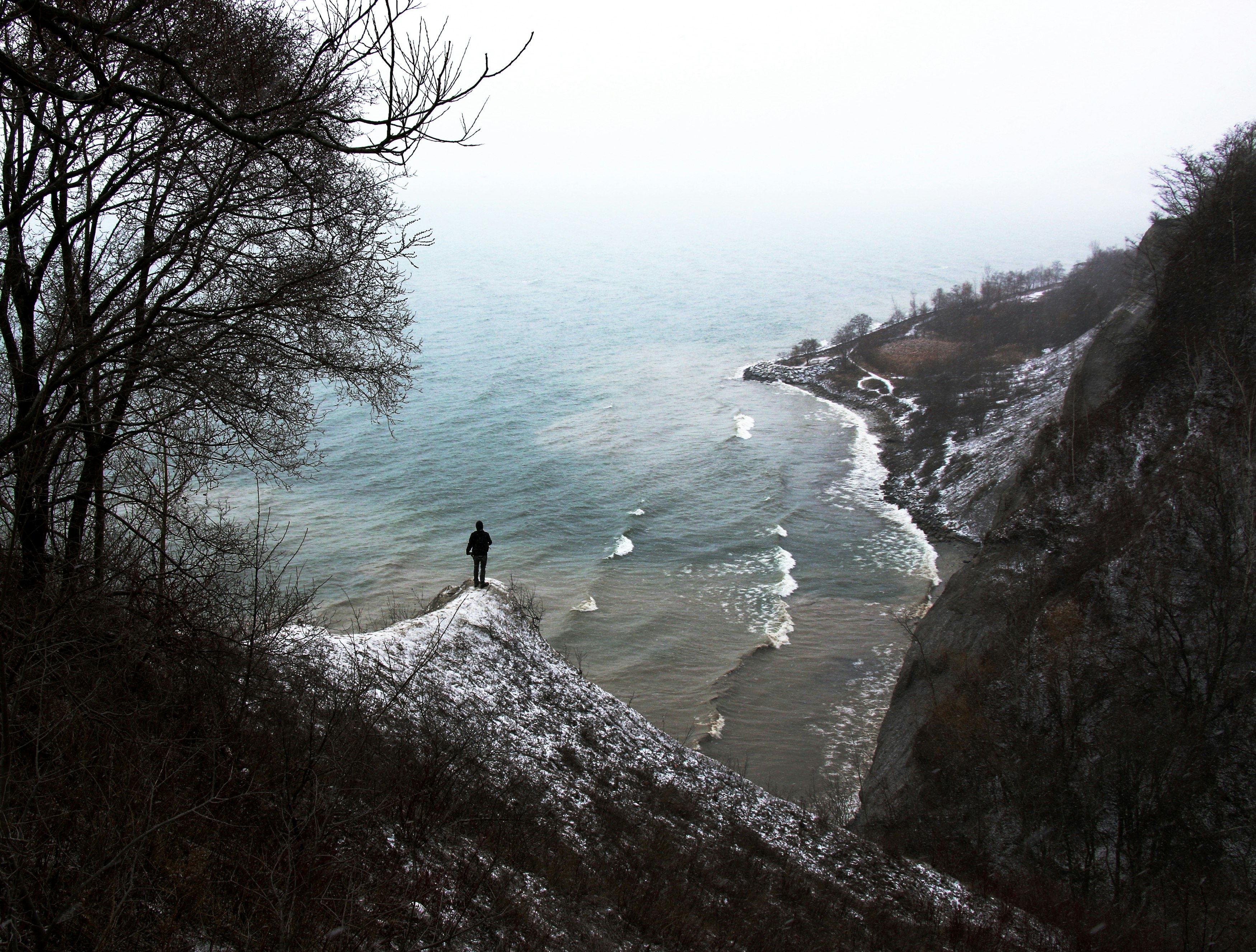 person standing on rock formation near the body of water